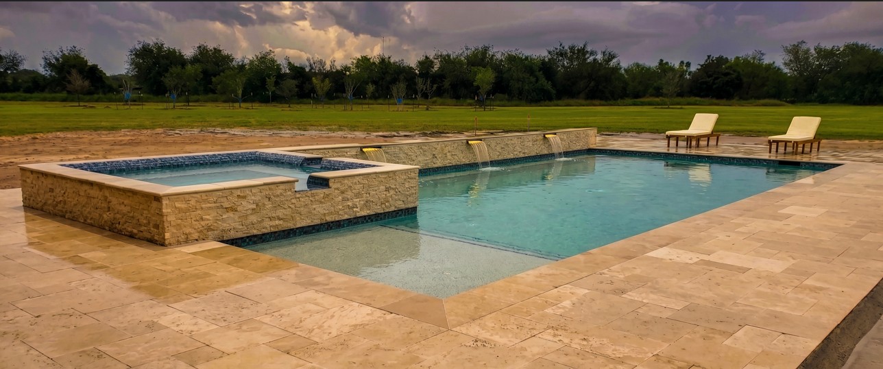Geometric pool with raised spa, raised wall with sheer descents, and travertine decking.